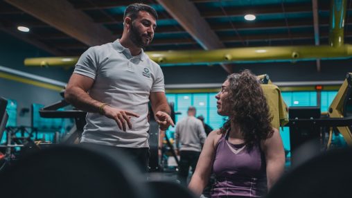 Sesión de entrenamiento en el gimnasio con un entrenador personal, enfocada en el rendimiento y el bienestar físico.